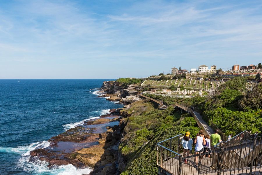 People walking to Waverley Cemetery along the Bondi to Coogee coastal walk in Sydney, Australia. A cliff top coastal walk featuring stunning views, beaches, parks, cliffs, bays and rock pools. Credit: Angelina Pilarinos/Shutterstock